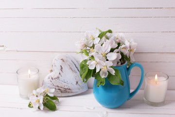 Apple tree flowers, heart and candles on white wooden background