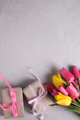 Bunch of  tulips and boxes with presents on textured grey backgr
