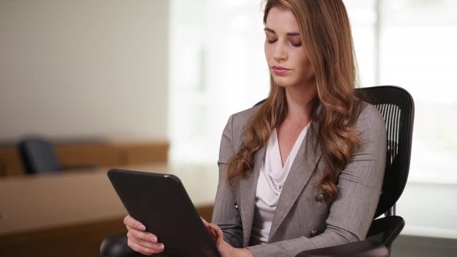 Professional Businesswoman in her 20s using tablet while sitting on her chair. Woman intern working on tablet in the office