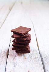Close up of a stack of crunchy wafer thin brownies on a wooden table.