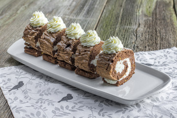 Chocolate roll filled with whipped cream on white tray
