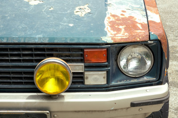 Detail of the front headlight of an old car in garage