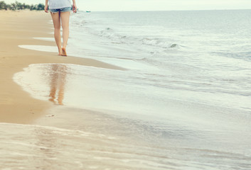 Closeup woman walking on sand beach leaving footprints in the sand, retro filter effect.