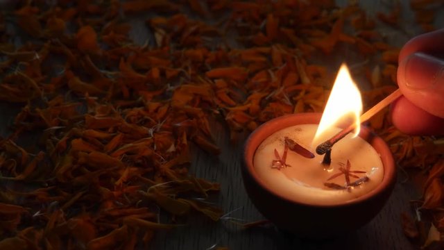 Close up of a Human lighting a Diya or a tradition lamp used for various Hindu festive celebrations for the festival of light- Diwali and also for others like Dussehra or prayers at home or a temple