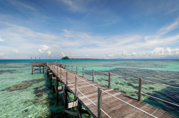 Wooden pier extending into the ocean over sea and corals.