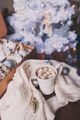 cup of hot cocoa with marshmallow with Christmas decorations at home, Christmas tree on background, cozy mood