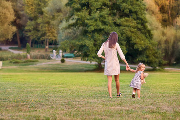 Naklejka na ściany i meble The concept of Mother's Day. Mother with little daughter walking