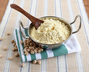 Fresh, homemade chickpea flour, in a steel utensil with a wooden spoon, and garbanzo beans.