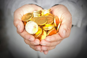Hands holding gold coins.