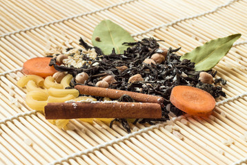 Dried tea, pasta, carrot and spices on wood background