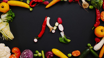 Vegetables made letter M. alphabet on a black table. The composition of bright ripe vegetables. M