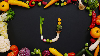 Vegetables made letter U. Alphabet made of vegetables.  Tomatoes, cabbage, peppers and other vegetables on a black background. U