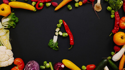 Vegetables made letter A. Tomatoes, cabbage, peppers and other vegetables on a black background. Vegetables are forming letters. A