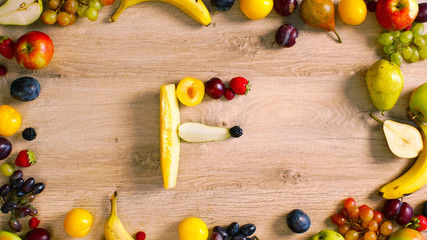 Fruits made letter F. The composition of bright ripe fruits. Alphabet on a table. F