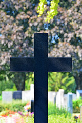 Dunkles Kreuz vor Grabsteinen