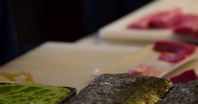 Sushi preparing and cutting raw tuna 4k  bokeh close up video. Japanese restaurant kitchen: chefs working, ingredients for rolls. Asian cuisine.