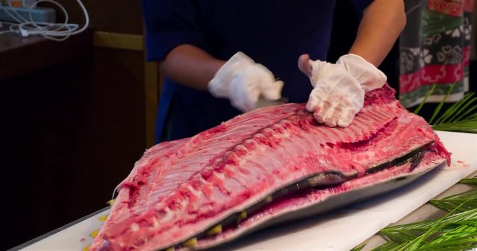 Chef hands cutting with knife raw bluefin tuna bones 4k video in sushi restaurant kitchen. Asian japanese cuisine.