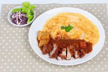 Omelet rice with deep fried chicken in Japanese yellow curry  with butter mashed potatoes salad  on gray. Side view.