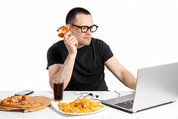 Man working at the computer and eating fast food. Unhealthy Lifestyle.