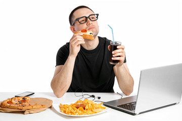 Man working at the computer and eating fast food. Unhealthy Lifestyle.