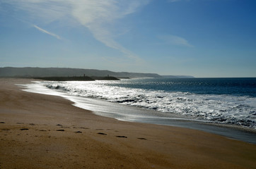Photo of the Atlantic ocean during sunset at the small touristic city Nazare with pharos on the background, Portugal