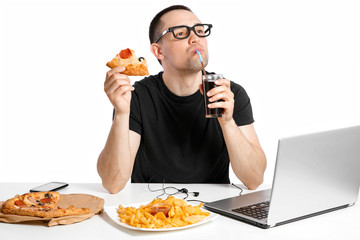 Man working at the computer and eating fast food. Unhealthy Lifestyle.