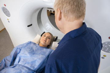 Patient Looking At Professional While Lying On MRI Machine