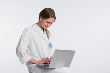 Smiling female doctor working on her laptop against a white background