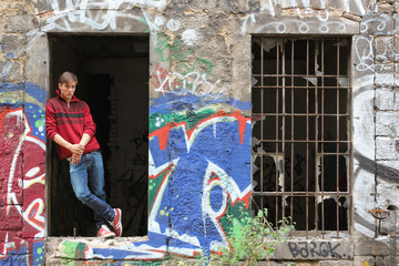Teenager steht rauchend im Fenster von Abrisshaus mit Graffiti