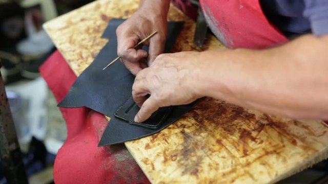 Calzolaio al Lavoro nella sua bottega artigianale. Ritaglio pelle nera per fondina Pistola. 