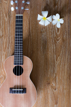 Ukulele on wooden background with white flowers