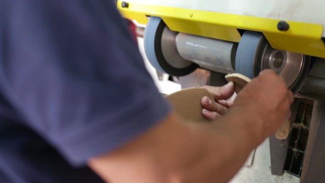 Calzolaio al Lavoro nella sua bottega artigianale. Levigatura suola per scarpe. 