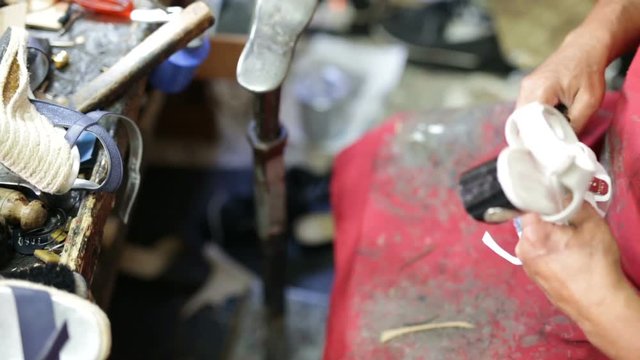 Calzolaio al Lavoro nella sua bottega artigianale. Ritaglio suola scarpa bassa per donna. 