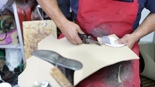 Calzolaio al Lavoro nella sua bottega artigianale. Ritaglio suola per scarpa da Donna. 