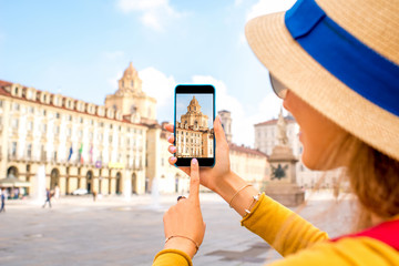 Woman photographing with smartphone saint Lawrence church on the central square in Turin in...