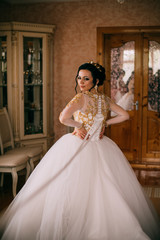 Fototapeta premium Close up portrait of pretty bride in hotel room. Woman in white dress decorated yellow beads. Girl in yellow golden crown. Luxury wedding day.