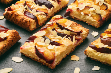 Slices of plum pie on black background.
