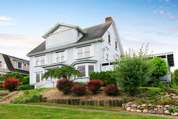 Traditional three story house exterior with well kept garden around.