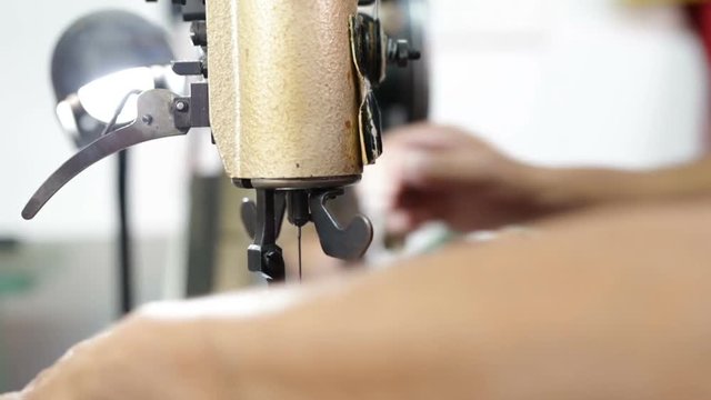 Calzolaio al Lavoro nella sua bottega artigianale. Cucitura di una fondina nera di pelle per Pistola. 