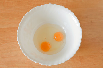 Two raw egg yolks in a white bowl. Top view
