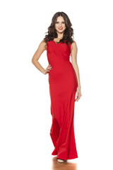 young beautiful woman walking in a long red dress on a white background