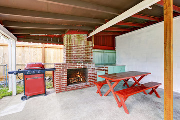Exterior covered patio with brick fireplace and furniture.