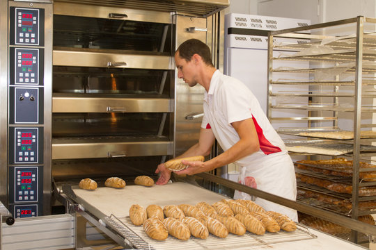 Baker standing in bakery in the morning and is baking bread