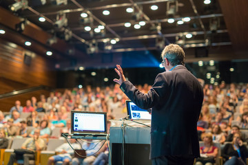 Speaker giving a talk on corporate Business Conference. Audience at the conference hall. Business...