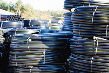 Fototapeta premium stacks of black pvc plastic pipe outdoors with selective focus