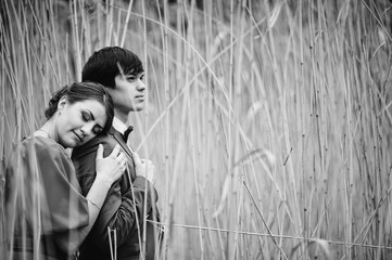Obraz premium Couple hugging in love at high cane. Stylish man at velvet jacket and girl in red dress in love together. Black and white photo
