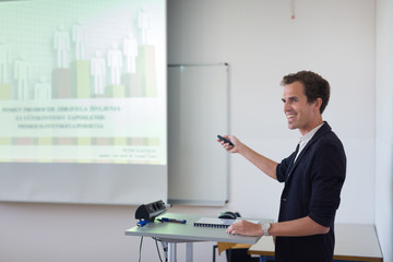 Relaxed confident smart student presenting his study work in front of whiteboard, defending his thesis. Doctoral thesis defense on faculty.