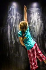 Girl child writing on the blackboard wall.