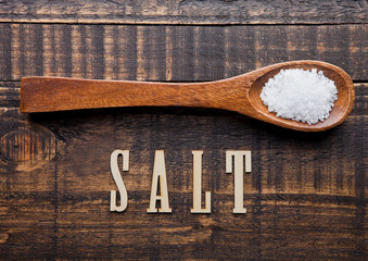 Salt on wooden spoon with letters below