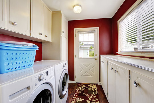 Laundry room interior with white cabinets and red walls.